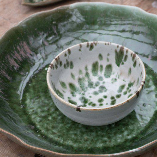 Green and off white speckled bowl on a wooden surface