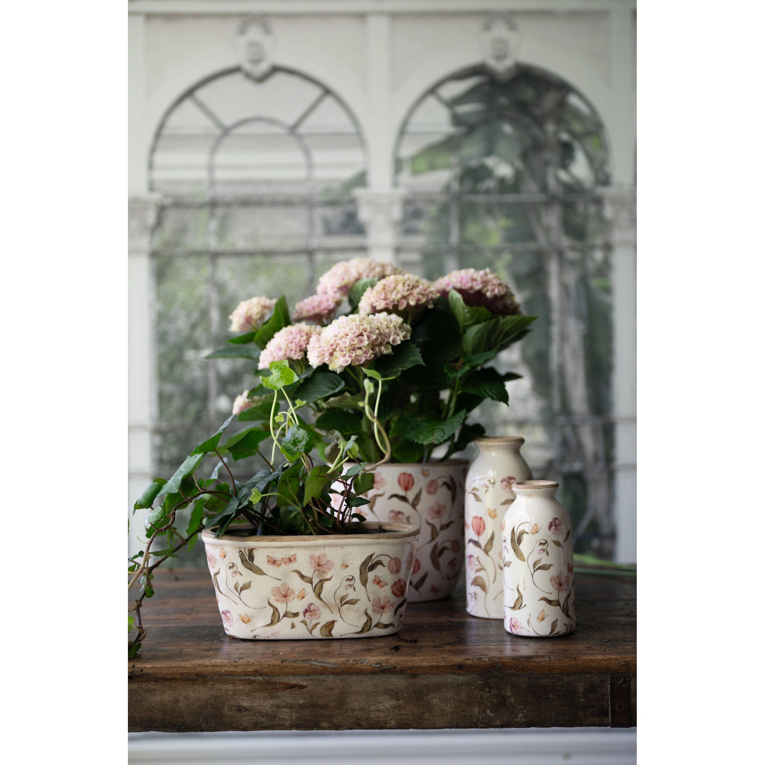 Lifestyle shot of Rhona vases and planter with floral design on a wooden surface.