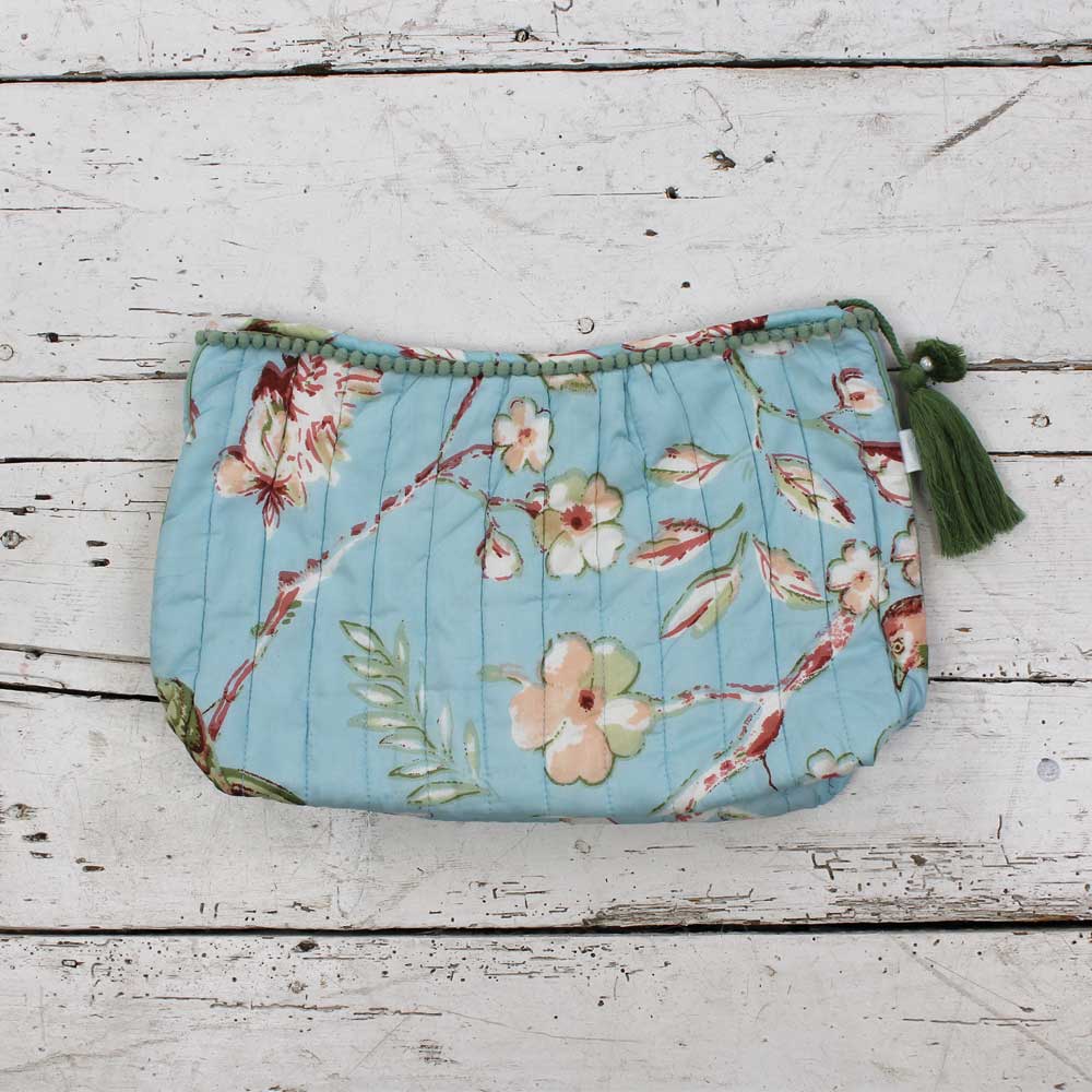 Blue wash bag with blossom print and green tassel.
