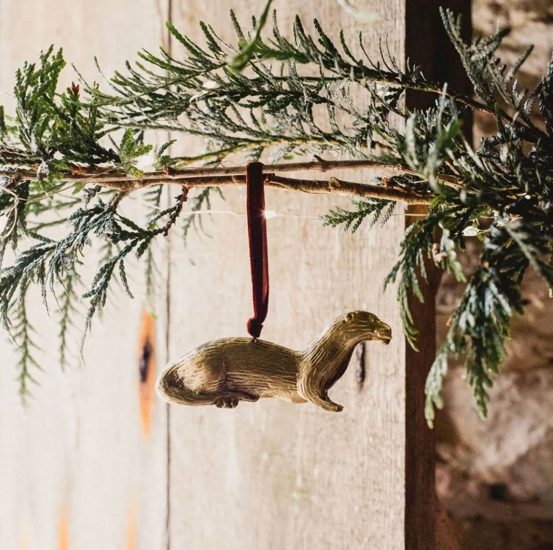 Brass otter-shaped hanging Christmas ornament.