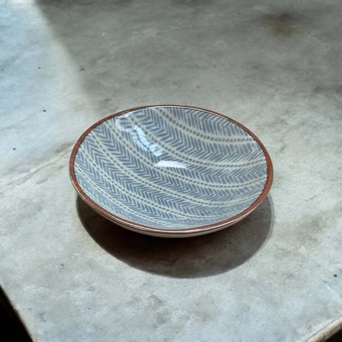 Ceramic plate with a blue geometric pattern on a white surface.