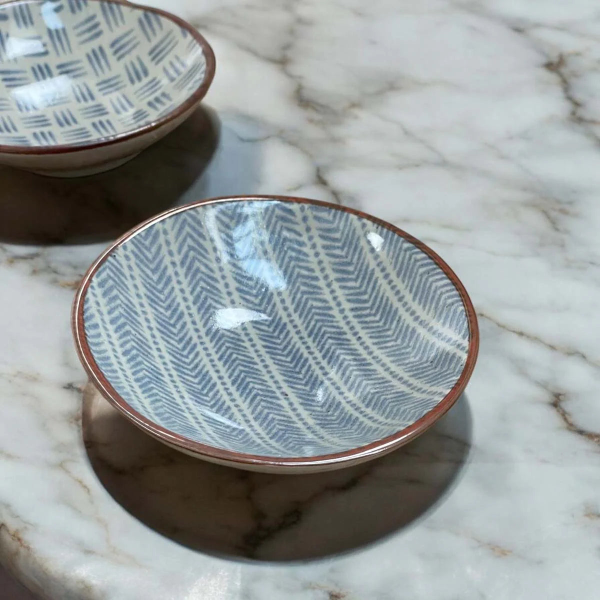Ceramic plate with a blue geometric pattern on a white surface.