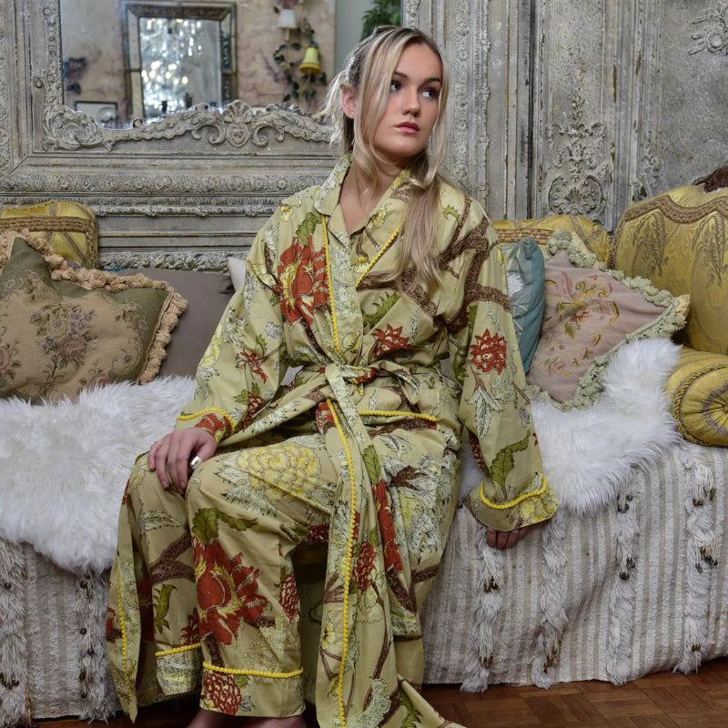 Woman in a Botanical Print Dressing Gowmn sitting on a decorative couch in an ornate room.