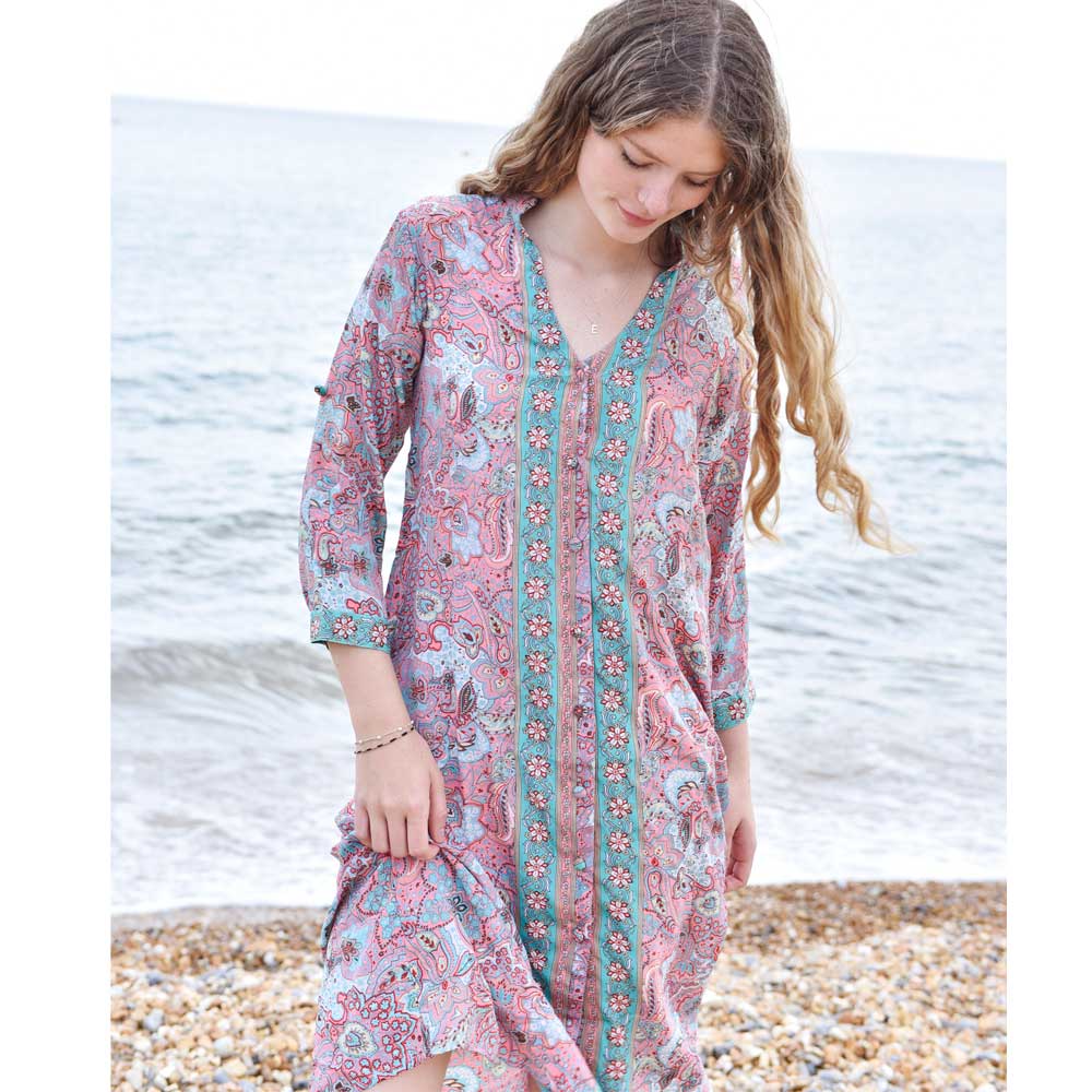 Pink floral shirt dress lifestyle shot on a stony beach by The Black Faced Sheep