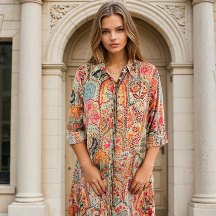 Woman wearing a colorful patterned dress standing in front of an architectural background