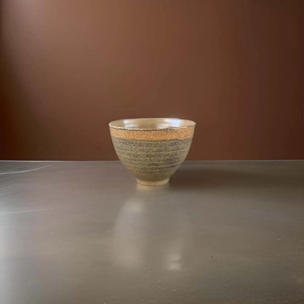 Gold ceramic bowl with speckled glaze.