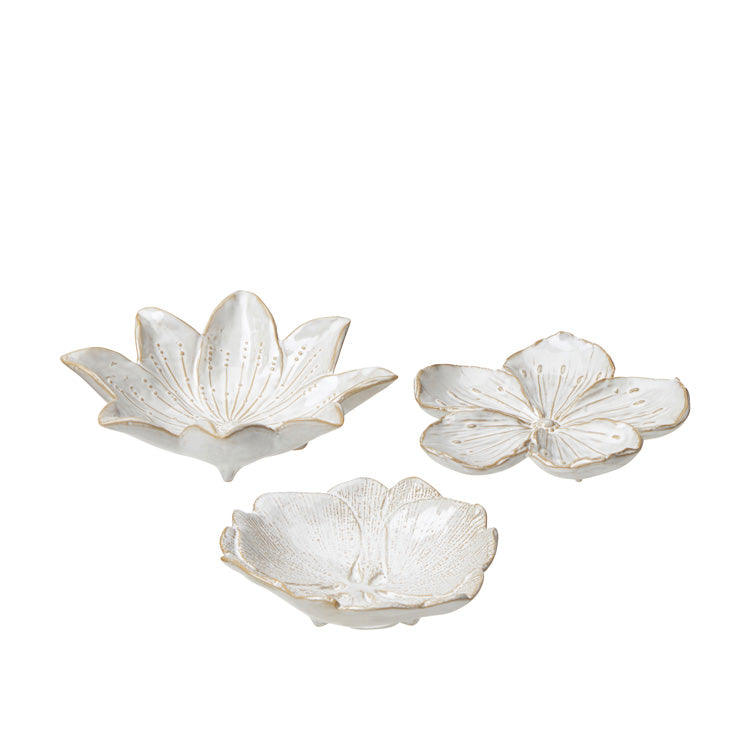 Three porcelain saucers in petal shapes, with white and beige color tones, displayed against a white background.