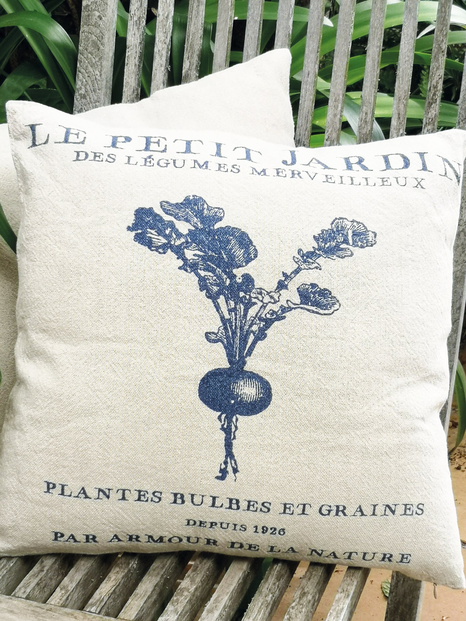 Decorative pillow with vintage-style design featuring a radish and text on a wooden bench.