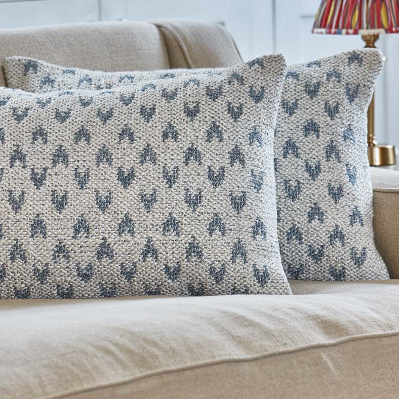 Mhari decorative cushions with blue heart design on neutral background on a beige sofa.