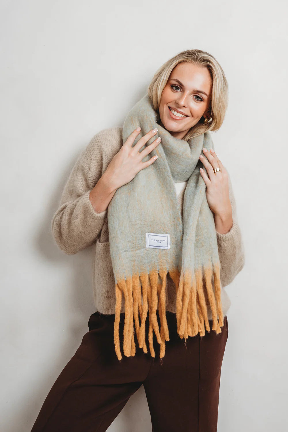 Turquoise winter scarf with yellow tassels.