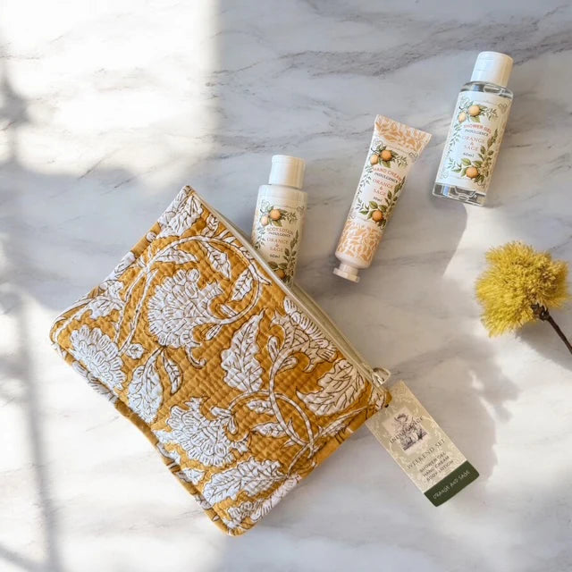 Weekend Kit. Three skincare products; hand cream, shower gel and body lotion, on a textured surface with block printed cotton pouch.