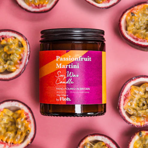Passionfruit Martini candle jar with a pink label on a pink background with passionfruit halves.