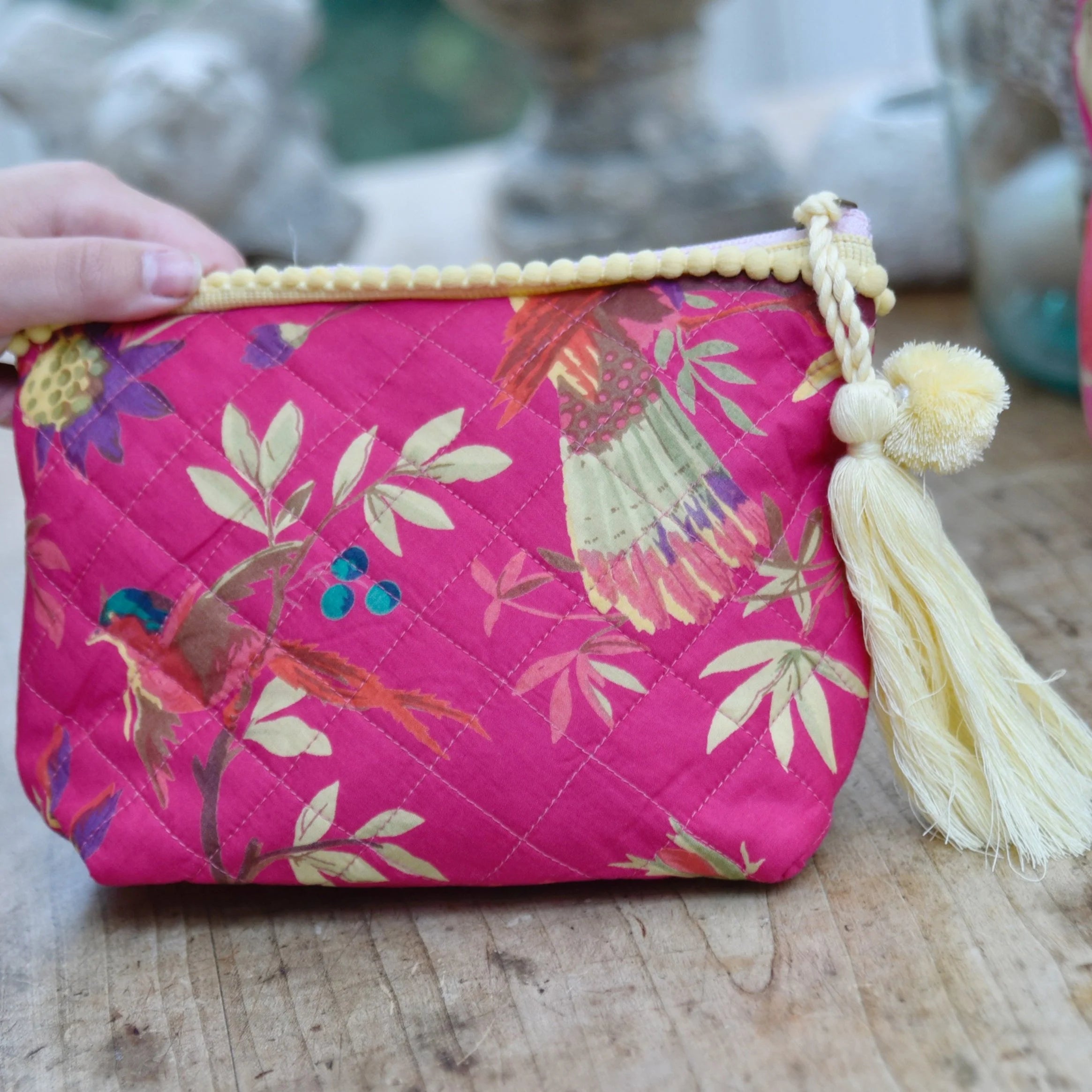 Fuchsia pink chinoiserie print make up bag with yellow pom pom trim.