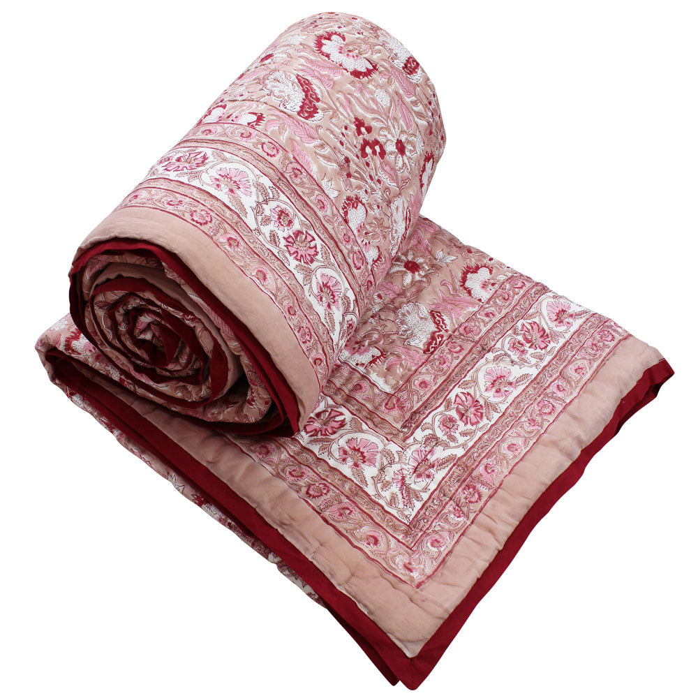 Pink and red reversible quilted throw in floral print.