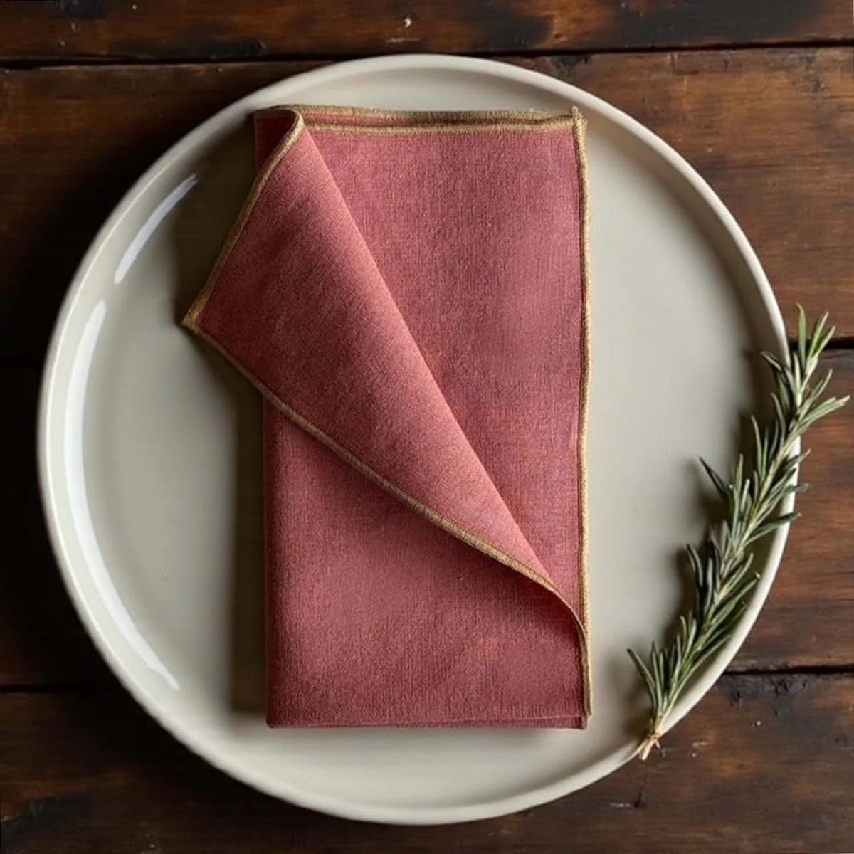 Rust coloured napkin with gold piped edges.