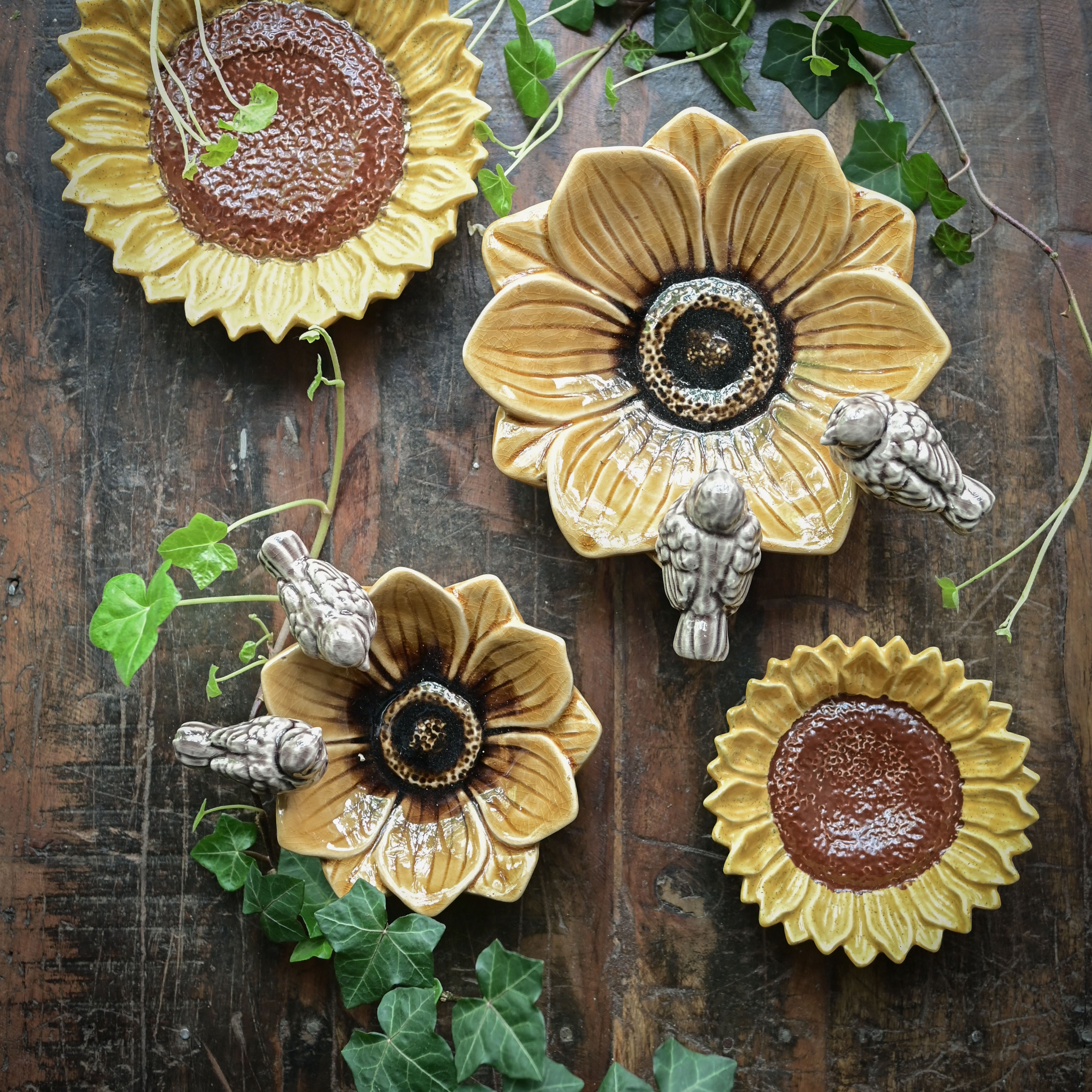 Decorative sunflower-shaped plates with floral designs on a wooden surface.