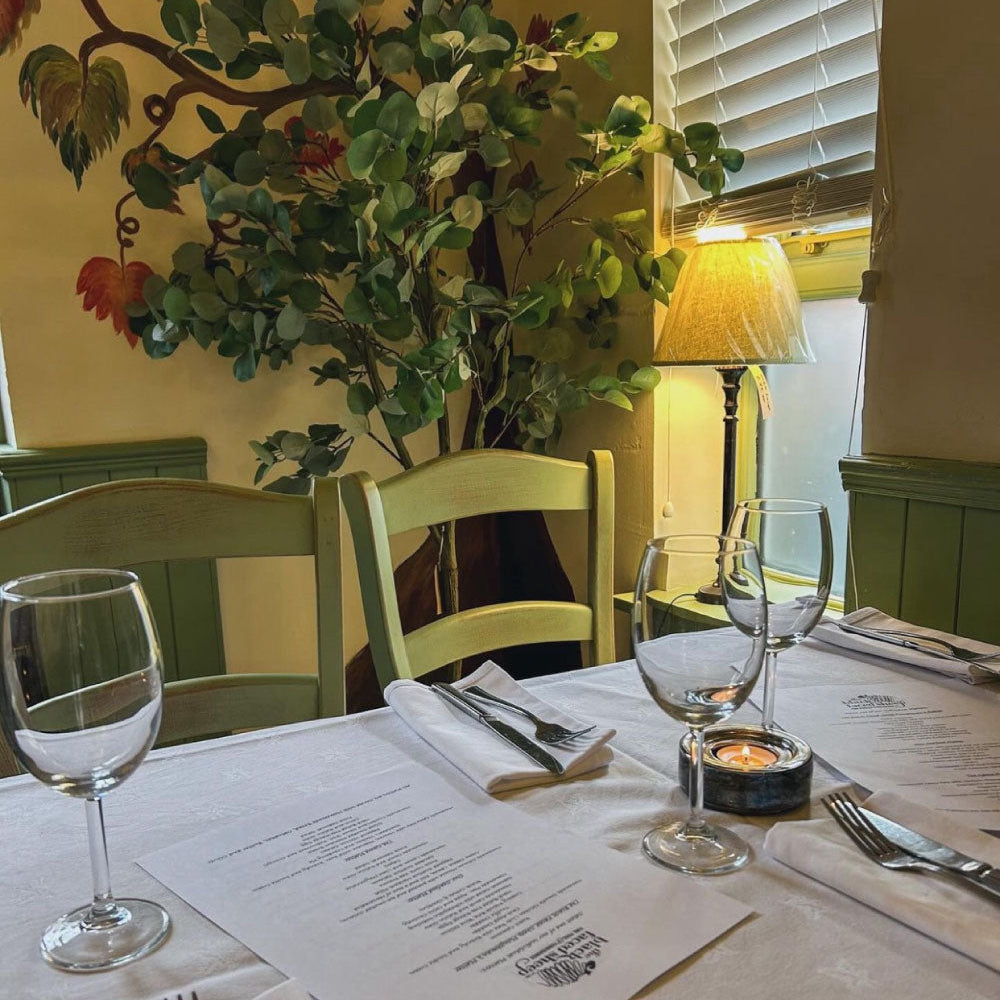 Evening dining at the Black Faced Sheep. Dining table setting with wine glasses, cutlery, and a menu.