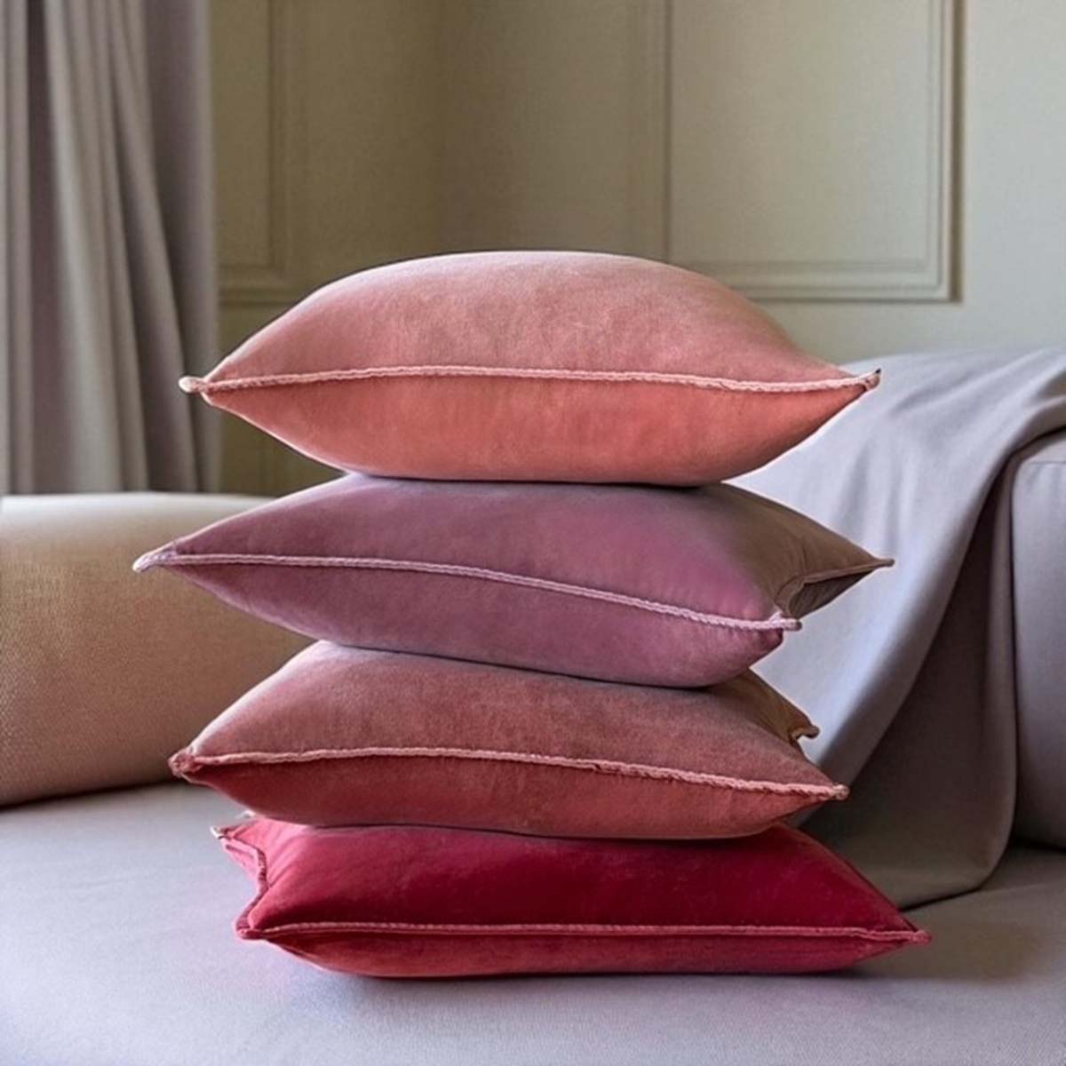 Stack of velvet cushions on sofa in shades of rust to pink