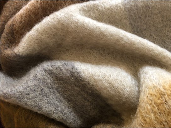 Detail of luxurious mohair throw made in Scotland showing softness and subtlety in honeycomb colours of ochre, grey and brown.