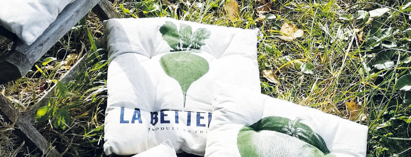 White pillows with vegetable illustrations and text on a grassy background