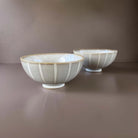 Ceramic bowls with stripes on beige surface.