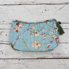 Blue wash bag with blossom print and green tassel.