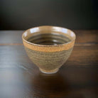 Gold ceramic bowl with speckled glaze.