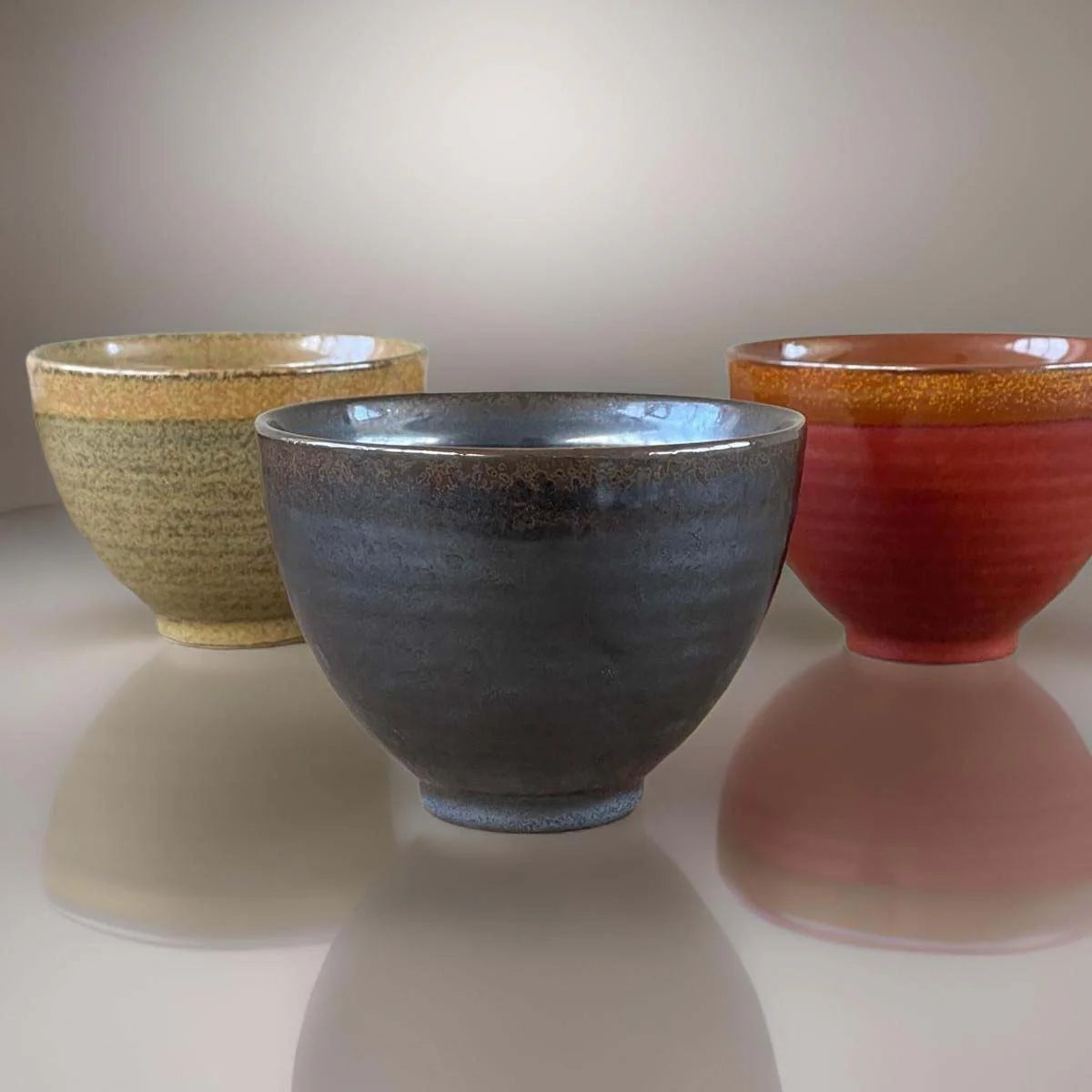 Three ceramic bowls with speckled glaze.