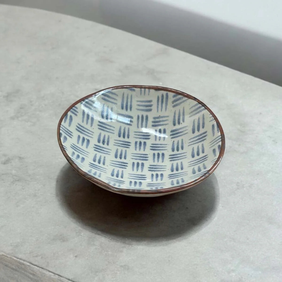Ceramic plate with a blue dash pattern on a white surface.