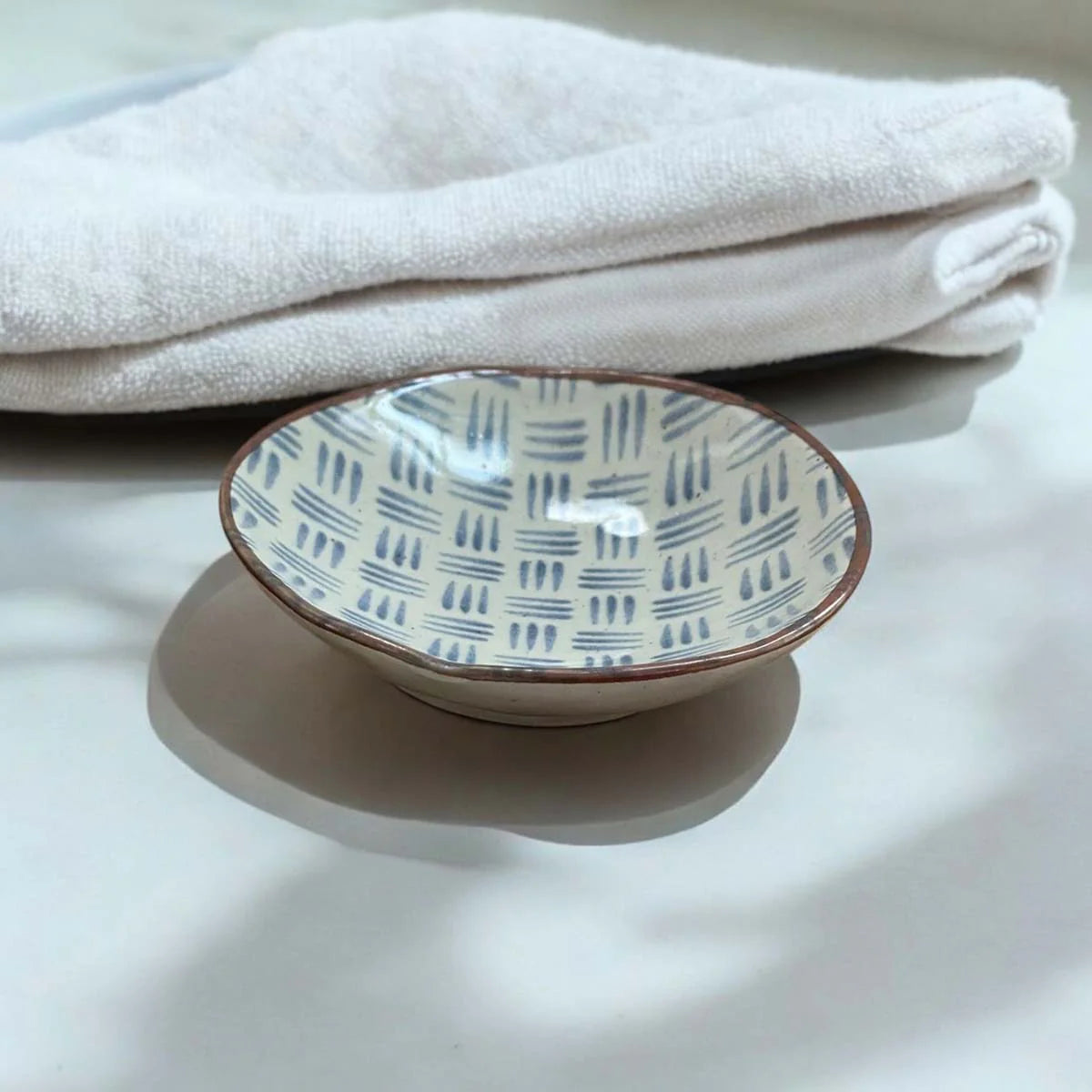 Ceramic plate with a blue dash pattern on a white surface.