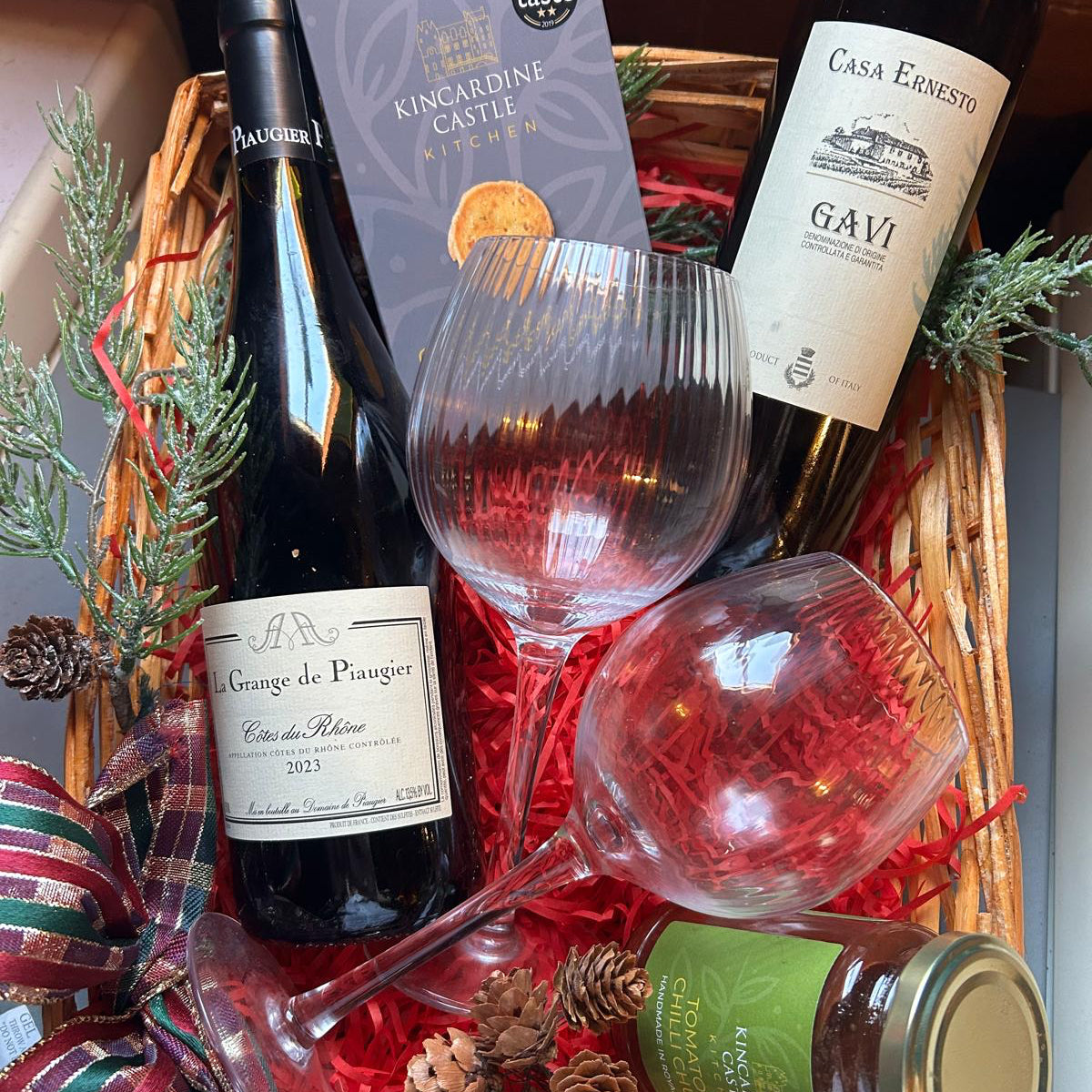 The Black Faced Sheep Cosy Christmas Eve Hamper, two bottles of red wine, with 2 wine glasses, and a jar of chutney  and special cheese biscuits.