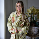 Woman wearing a Botanical Print Dressing Gown  in a room with orchids.