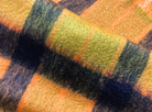 Detail of this traditionally woven Marigold mohair throw,  inspired by traditional tartans in bold, bright colours of yellow and orange and dark navy. The special drawn finish creates exceptional warmth and lustre.