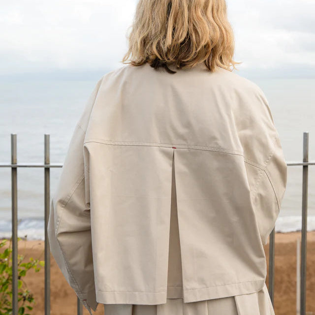 Person wearing a cotton jacket standing with their back to the camera, overlooking a scenic view.