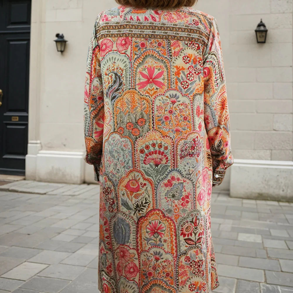 cream orange long, patterned dress standing on a street.