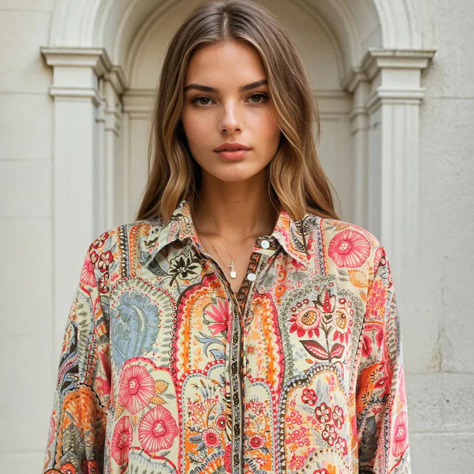 Woman wearing a colorful patterned shirt standing in front of a classical building.