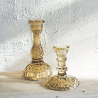 Two Tilda Glass Candlesticks in Vintage Pink on a textured white surface