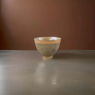 Gold ceramic bowl with speckled glaze.