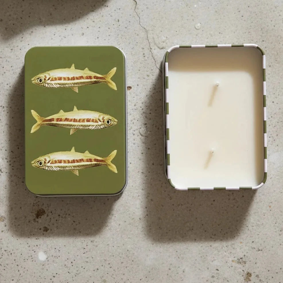Candle in a tin with fish design on a textured surface