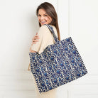 Woman carrying a large blue floral-patterned bag against a white background