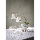 Decorative setup with glass lantern candle holders and a branch on a textured surface.