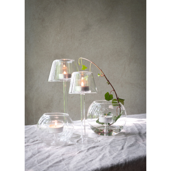 Decorative setup with glass lantern candle holders and a branch on a textured surface.