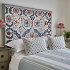 Bedroom with a decorative headboard, striped bedding, and Mhari cushion in blue.