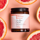 Paloma Breeze soy wax candle with grapefruit slices on a pink background