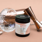 Candle jar labeled 'Paloma Breeze' by Flos on a beige background with decorative elements.