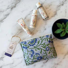 Three skincare products on a textured surface with a blue and green fabric pouch.