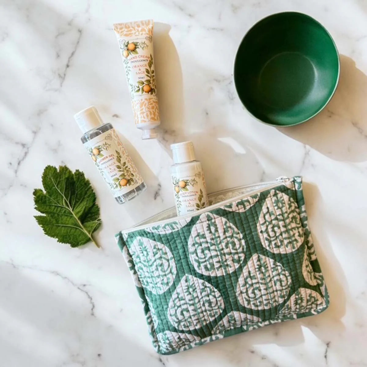 Three skincare products on a textured surface with a green fabric pouch.