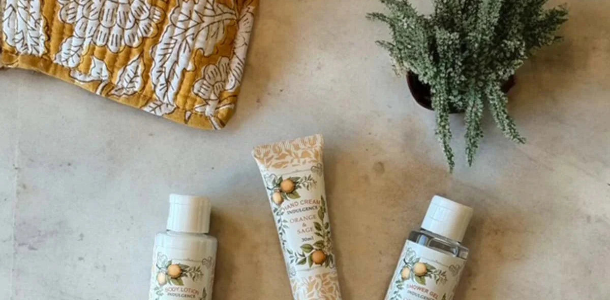 Three skincare products on a textured surface with a yellow fabric pouch.