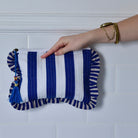 Blue and White Wide Stripe Seashell makeup bag back view of stripes held by hand against a white tiled background
