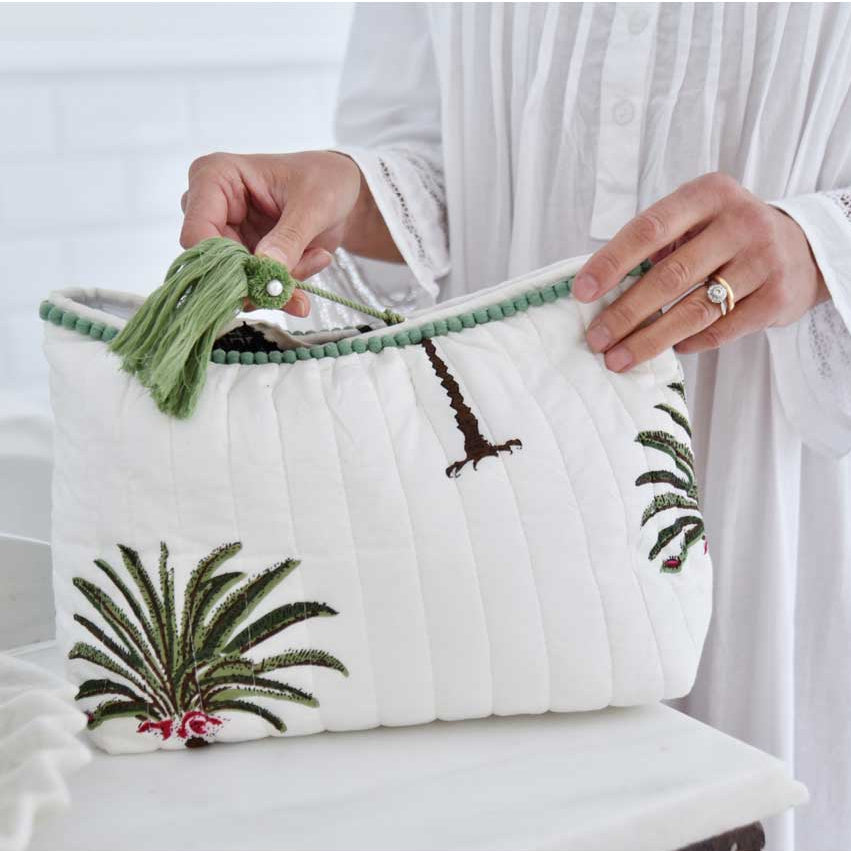 Palm tree print wash bag on white background with green pom pom trim.
